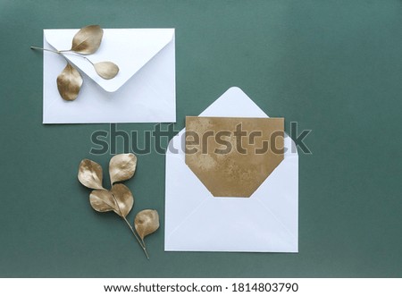 greeting cards mockup template, invitations blank in white, gold colors and gold leaves  on green  background. Flat lay, top view, copy space