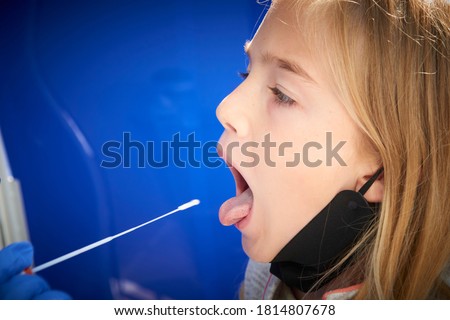 Taking a medical sample - a throat swab for a coronavirus test. Nurse takes a sample from child blond girl for Covid 19 test. An unpleasant experience for children Royalty-Free Stock Photo #1814807678