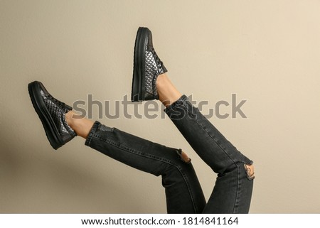 Woman wearing shoes on beige background, closeup
