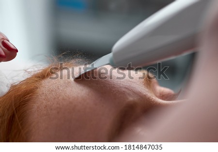 close-up photo of woman receiving stimulating electric treatment on forehead. beauty, skin care concept