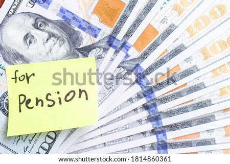 Yellow stick note on an USD 100 dollars money fan background. The inscription "For pension" on a yellow memory sticky note. Close up