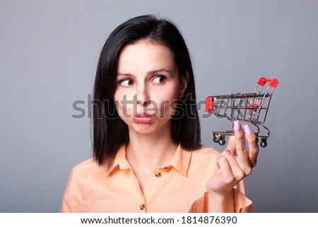 woman in orange shirt holding a small shopping cart