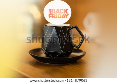 Picture of a black cup with an abstract pattern on the table. Black Friday sign over the cup