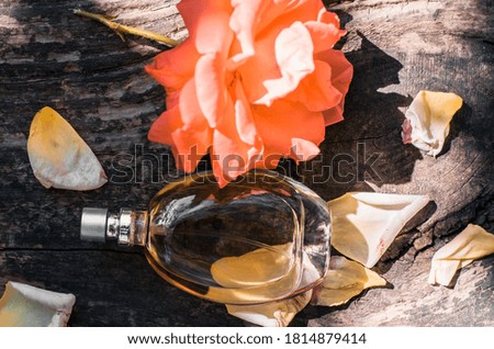 Perfume bottle with roses on a wooden background.