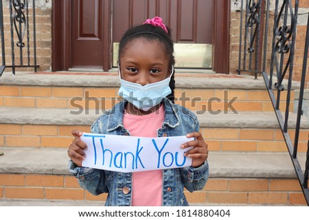 Girl holding thank you sign outside house front steps and door background