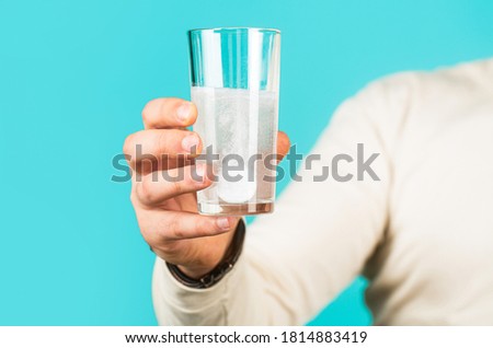 White pill and a glass of water in man hands. Health concept. Close up of man holding a pill. Glass of water tablet. Glass with efervescent tablet in water with bubbles.
