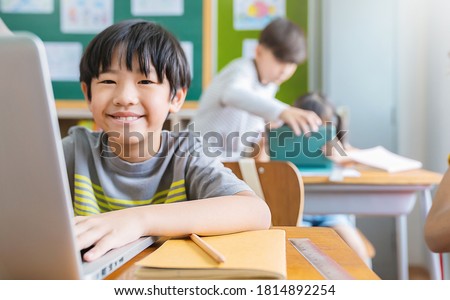 Portrait of Asian boy using computer to learn lessons in elementary school. Student boy studying in primary. Children with gadgets in classroom. Education knowledge, technology internet network. Royalty-Free Stock Photo #1814892254
