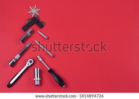 Creative christmas tree on red background, made of wrenches.Set of tools supplies for repair car on xmas backdrop. Industrial greeting card and christmas happy new year concept. Royalty-Free Stock Photo #1814894726