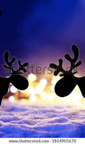 Magic winter christmas background with christmas lights, silhouette deer and snow at night.