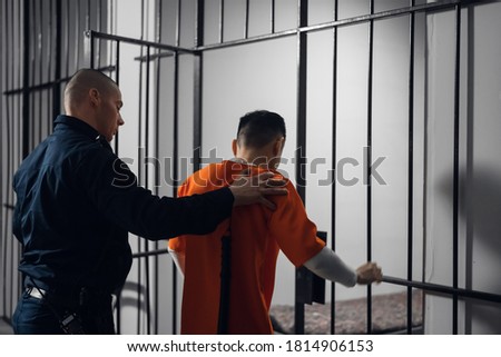 The prison warden puts the prisoner behind bars after the court verdict and locks the cell Royalty-Free Stock Photo #1814906153