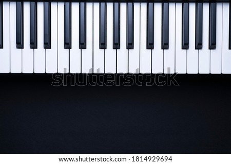 PIANO KEYBOARD ON BLACK BACKGROUND WITH COPY SPACE FOR TEXT. TOP VIEW.
