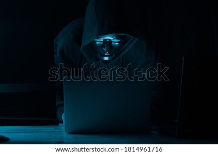 Hacker and malware concept. Dangerous Hooded hacker man using laptop Hacking the Internet.