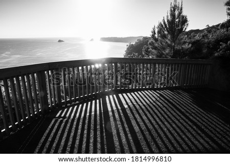 Lookout barrier with long shadows of structure on Coromandel coast in monochrome.