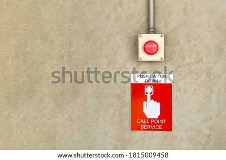 fire alarm call point service sign label with red color push button switch on cement wall.