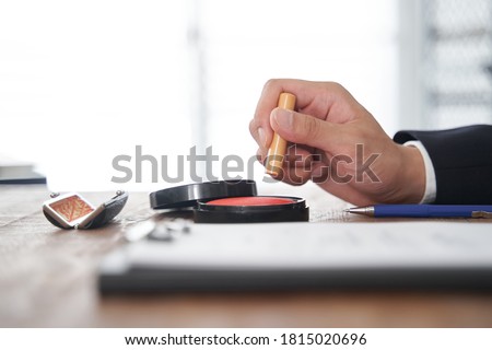 A Japanese male businessman who stamps his personal round seal on documents Royalty-Free Stock Photo #1815020696
