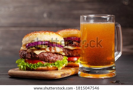 Two homemade tasty burgers with big beef, cheese, tomato, bacon and lettuce and lager beer mug