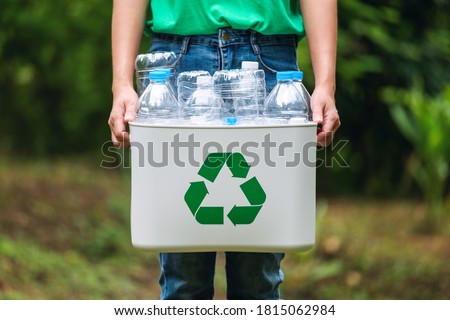 A woman holding a recycle bin with plastic bottles in the outdoors Royalty-Free Stock Photo #1815062984