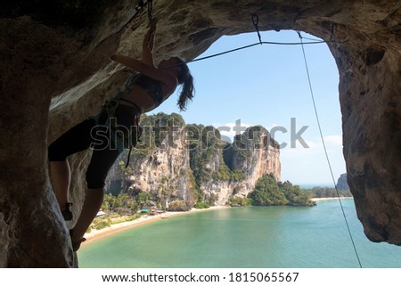 Climber  climbs the ceiling of the cave on the background of beautiful tropical landscape. Tonsai beach, Krabi Province, Thailand.