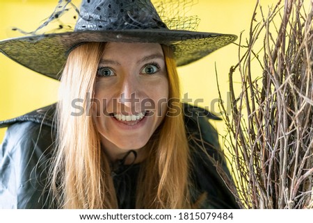 A witch in a hat with crazy eyes looks at the camera.women in a carnival costume with a broom. Halloween party