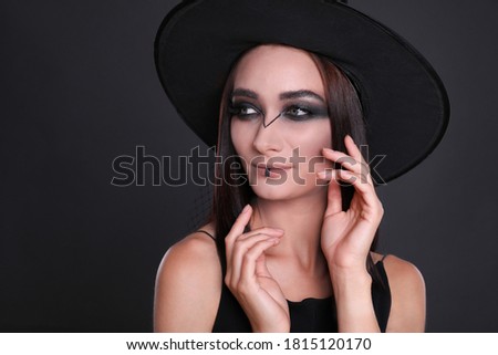 Mysterious witch wearing hat on black background, closeup