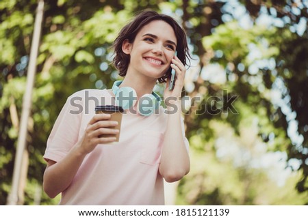 Photo of charming lovely cute lady cheerful look hands hold telephone cup coffee talking grandmother asking some pies cook appoint meeting family dinner wear headphones white shirt outside