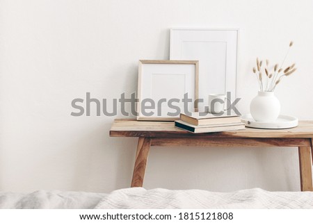 Portrait and square wooden picture frames mockups. Vintage bench, table with modern ceramic vase, bunny tail dry grass, books and cup of coffee. White wall background. Scandinavian interior. 