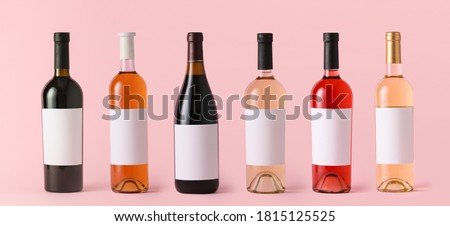 Bottles of wine with blank labels on color background. Mockup for design Royalty-Free Stock Photo #1815125525