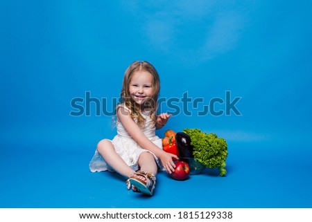 little girl near vegetables on a blue background