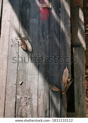 Image for background ; top view wooden surface with shadow and dry leafs.Image may contain noise or grain due to low light.