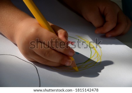 little children draw with colored crayons at a white table in the garden princess and the first attempts to properly hold a pencil on paper in kindergarten