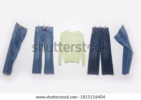 Front view fashion four blue jeans with green sweater on hanging
