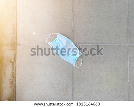 Dirty surgical mask on cement floor with space for your text and design. Concept for protect pollution, virus, corona virus and respiratory infection. Blur picture.