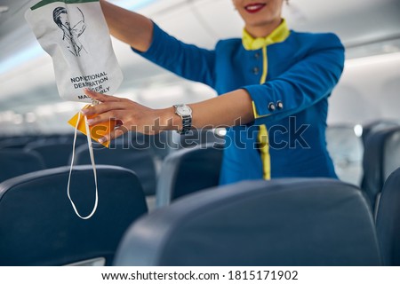 Close up portrait of hands of flight attendant on a commercial passenger jet reaching for an oxygen mask Royalty-Free Stock Photo #1815171902