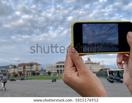 A girl takes a picture of a city landscape on her phone