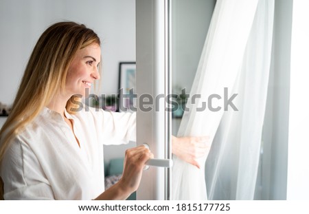 Beautiful smiling woman opening window at the morning Royalty-Free Stock Photo #1815177725