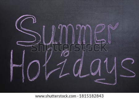 Phrase SUMMER HOLIDAYS written on black background. School's out