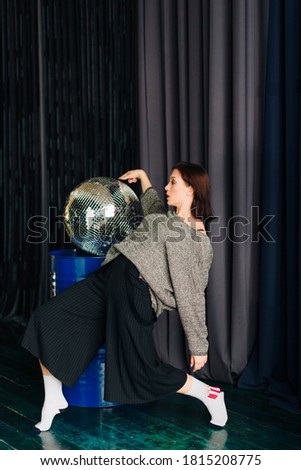Beautiful young woman in grey sweater and disco ball at home