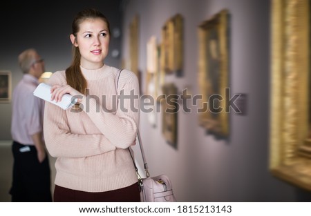 Portrait of brunette woman looking at pictures and amaze in museum