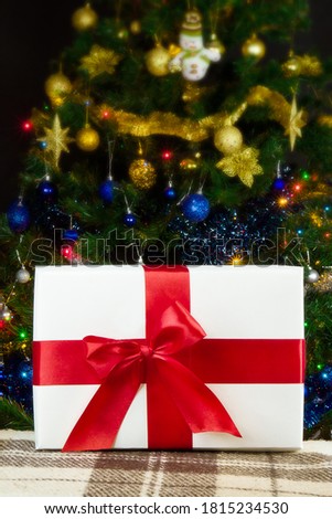 white box with red ribbon on christmas tree background