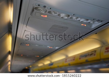 Air conditioning or ventilation knobs and reading light lamps above passenger seats in airplane, closeup detail