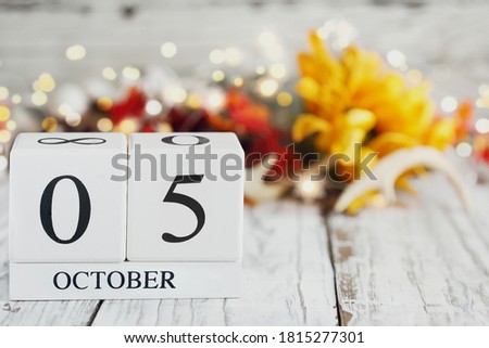 White wood calendar blocks with the date October 5th and autumn decorations over a wooden table. Selective focus with blurred background. World Teachers' Day.