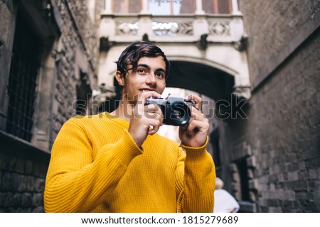 Cheerful caucasian male traveler enjoying visiting town making picture on camera exploring historic places, smiling man tourist taking photo satisfied with spending vacation free time on hobby