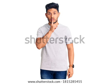 Handsome latin american young man wearing casual tshirt asking to be quiet with finger on lips. silence and secret concept. 