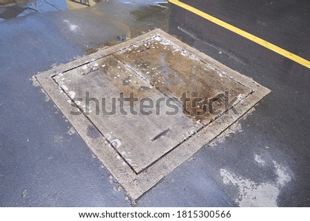 Concrete pipe cap plates with flooding water and bubble. Drainage cover on street. Sewer drain on the pavement.