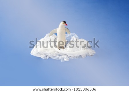 Penguin toy entangled in a plastic bag on blue background. Concept of plastic pollution. Environmental Problem. Copy space for text