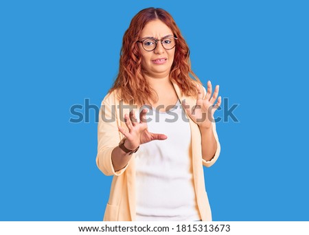 Young latin woman wearing business clothes disgusted expression, displeased and fearful doing disgust face because aversion reaction. with hands raised 