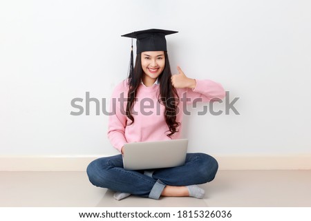 Young attractive Asian woman sitting with laptop on her legs wearing graduated hat, online education class, scholarship study abroad concept. Royalty-Free Stock Photo #1815326036