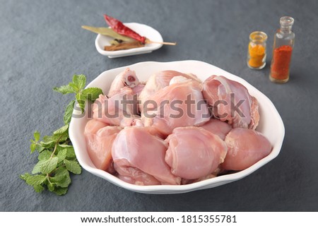 Fresh raw chicken pieces cut for biriyani with spices on grey stone background