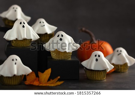 Halloween fondant ghost cupcakes on black podiums.  Halloween party food idea.