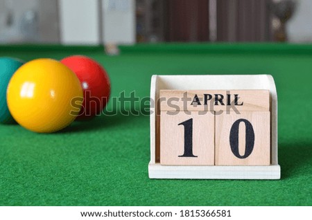 April 10, number cube with balls on snooker table, sport background.